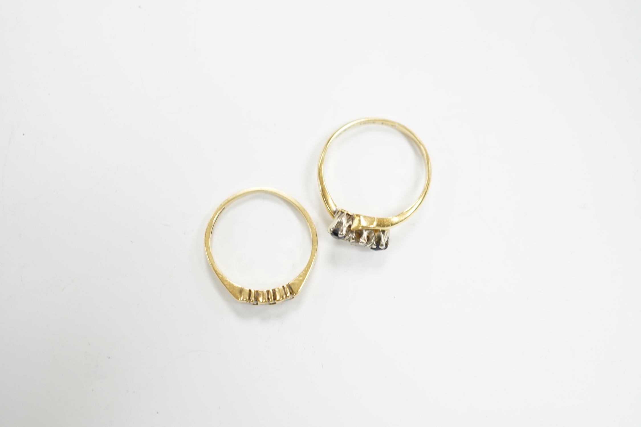 An 18ct gold and three stone diamond ring, size M and an 18ct, sapphire and diamond set three stone crossover ring, size O, gross weight 5.4 grams.